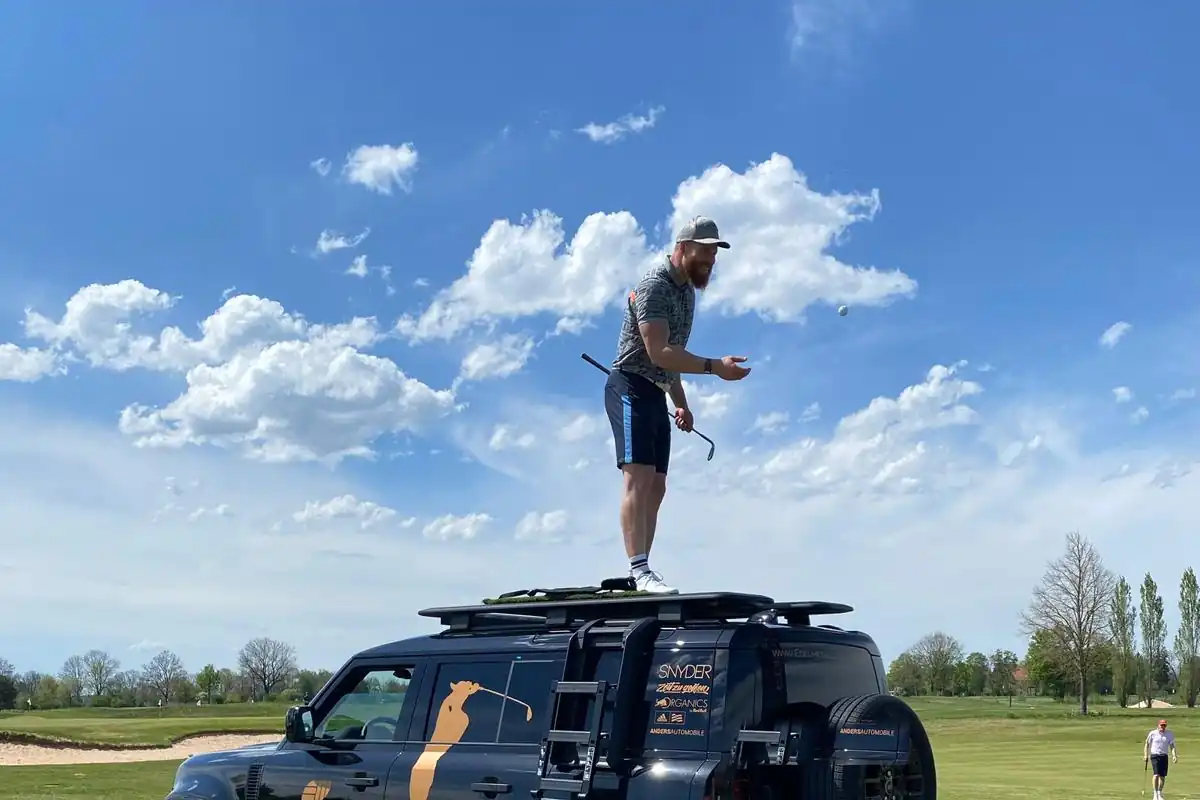 Teilnehmer bei der Defender Challenge auf dem Fahrzeugdach vor dem Abschlag