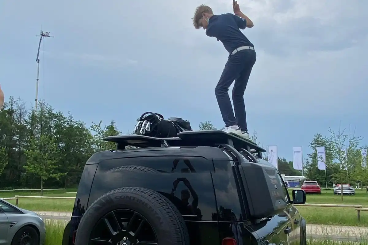 Golfer beim Abschlag vom Defender-Dach aus der Heckansicht