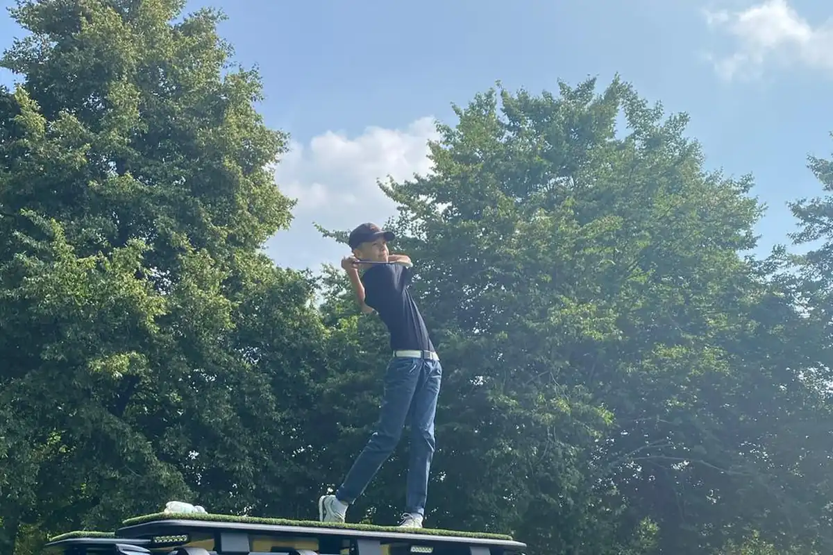 Jugendlicher Teilnehmer beim Abschlag vom Defender-Dach auf dem Golfturnier